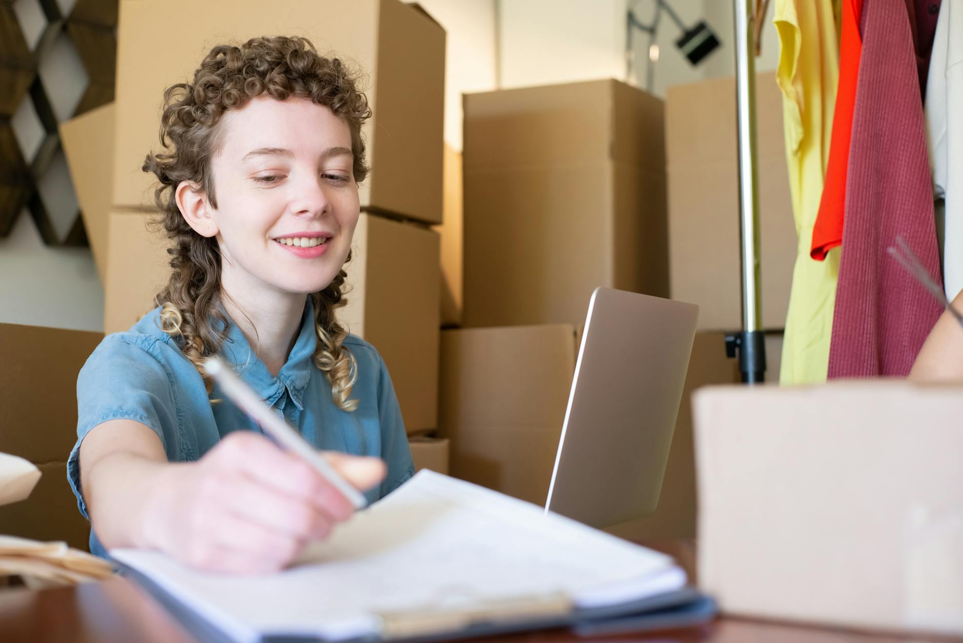 Woman at desk with laptop and boxes setting up an online business presence