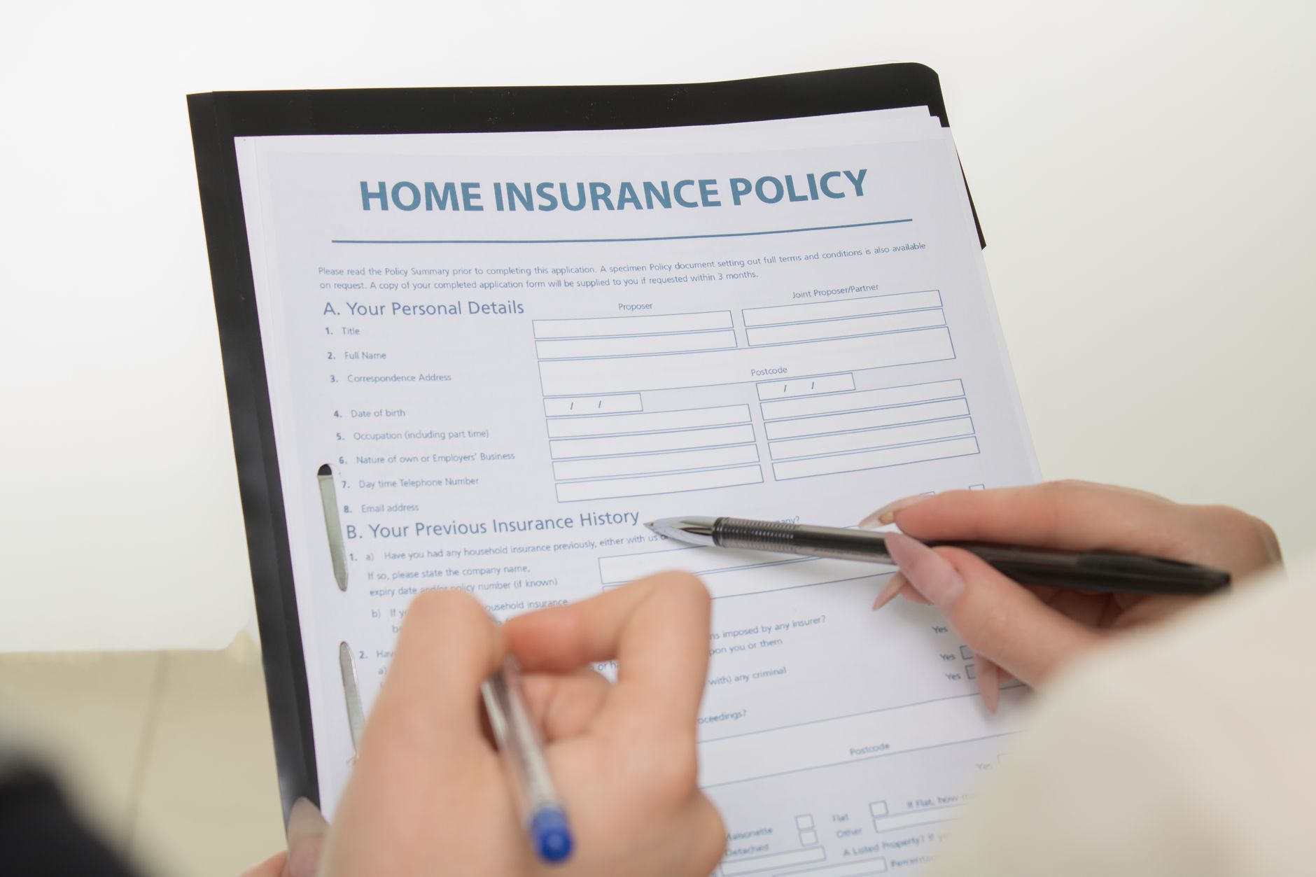 Insurance policy documents on a desk with a pen and reading glasses