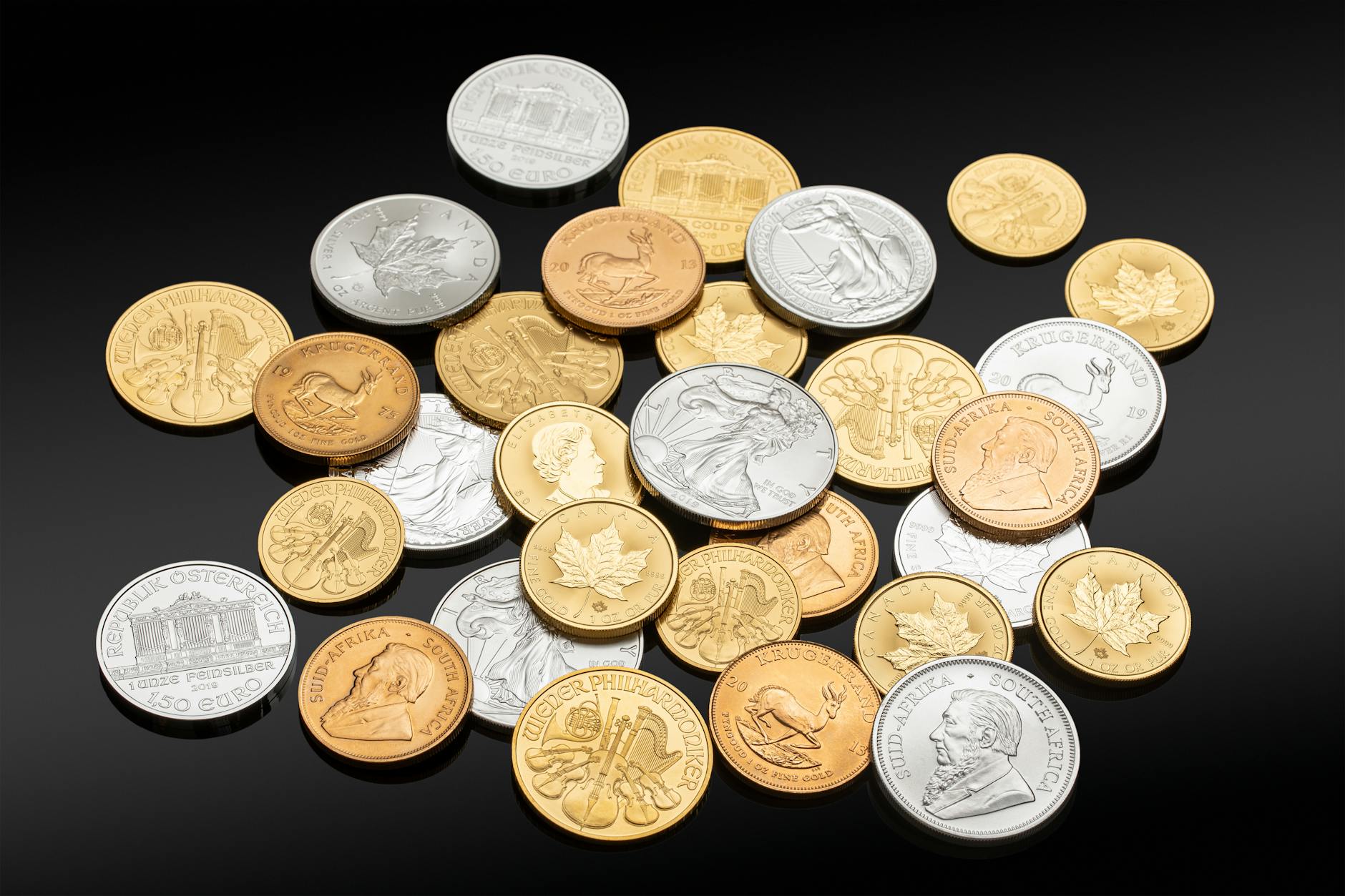 Silver and gold coins on a dark surface showing physical precious metal investment
