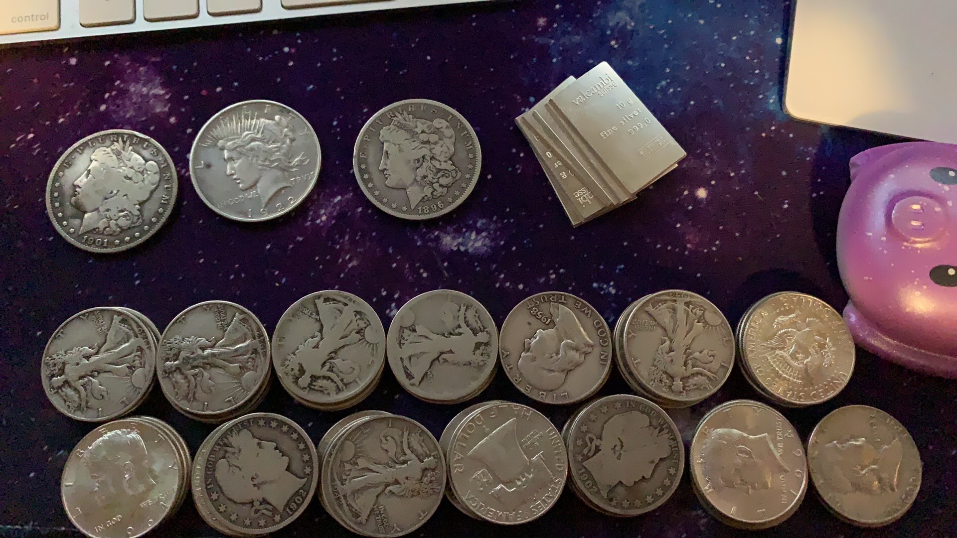 Morgan dollars and mixed silver coins spread out on a dark surface