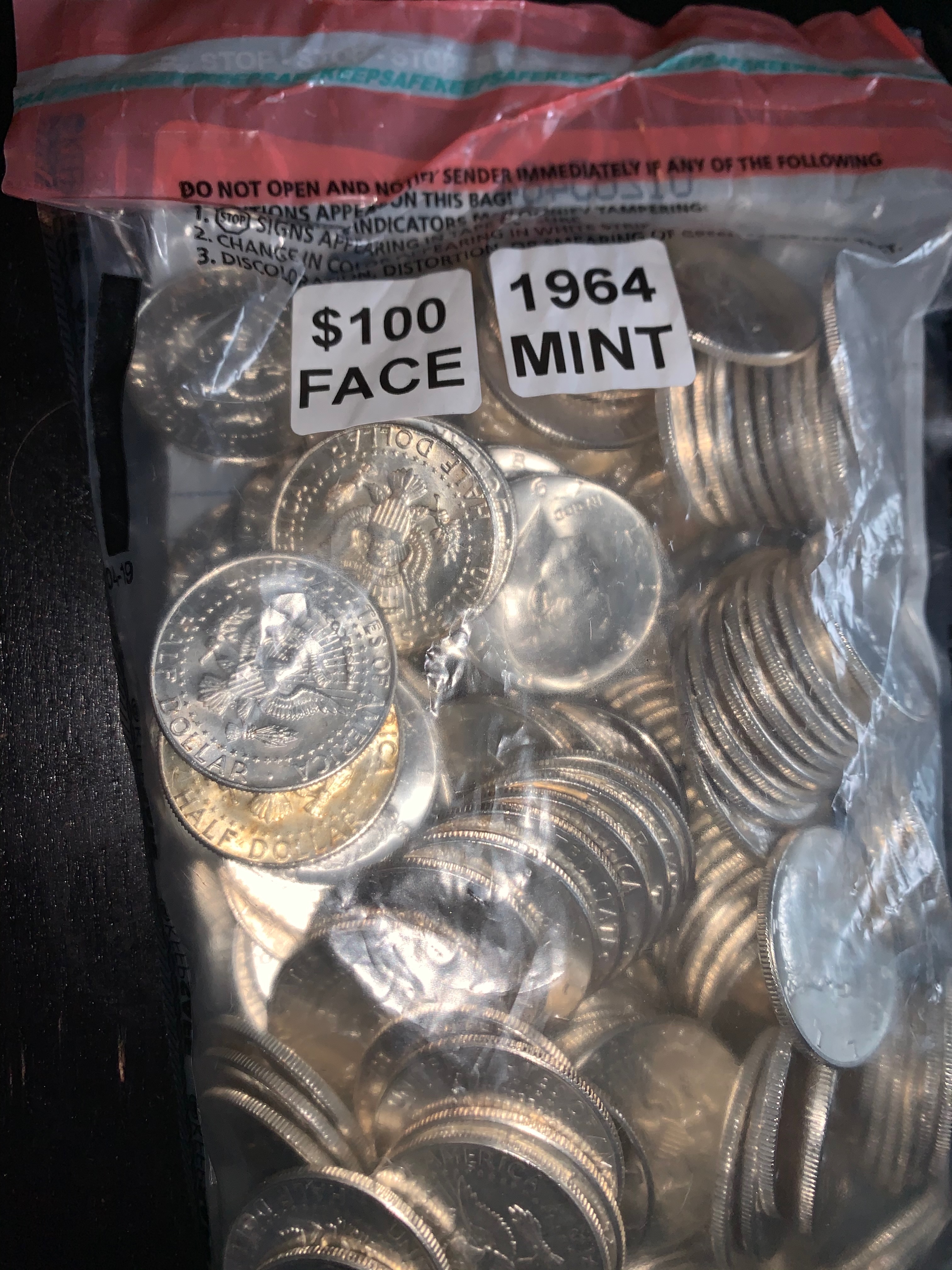 Sealed bag labeled $100 Face 1964 Mint full of Kennedy half dollars