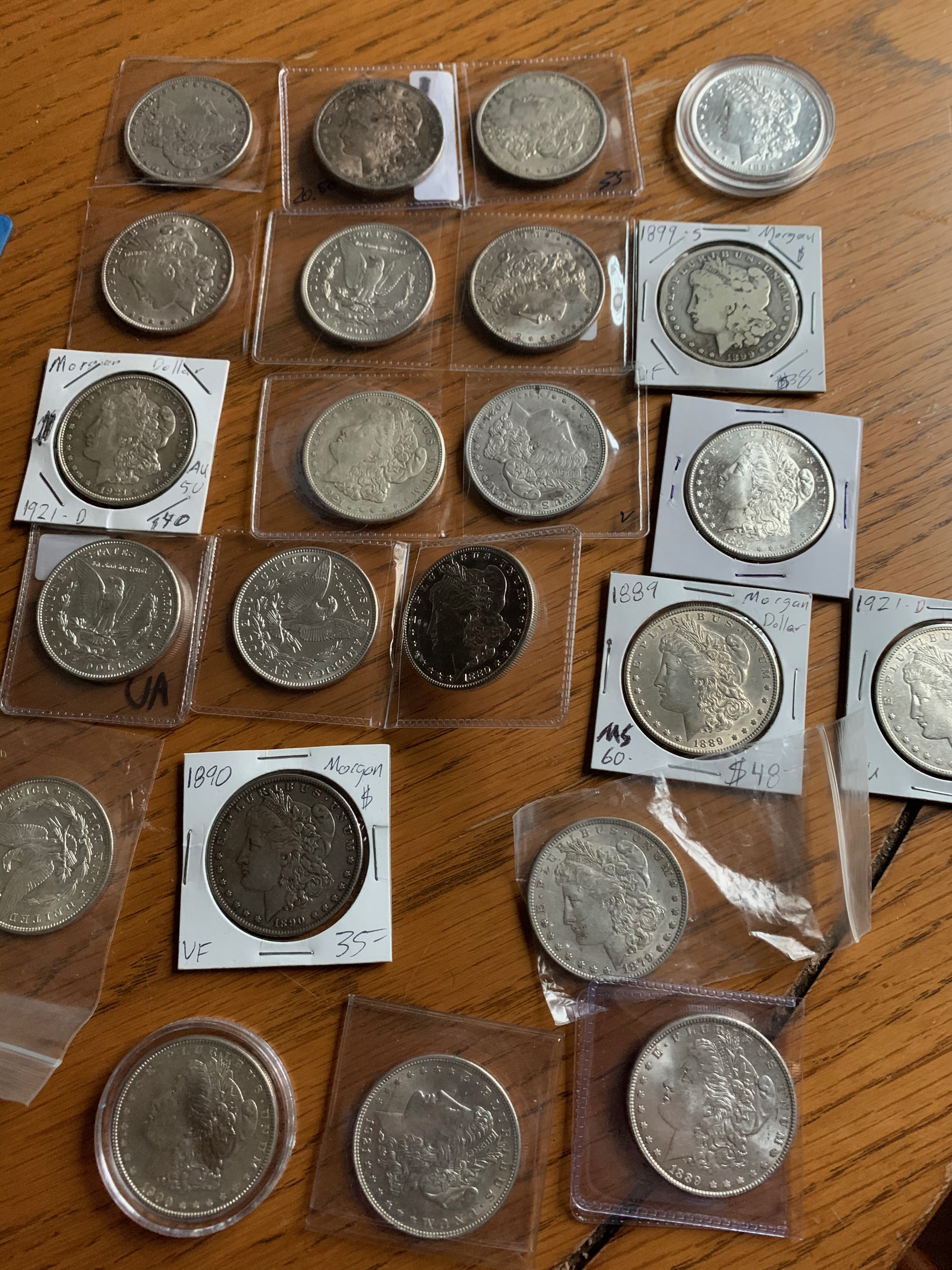 Large lot of Morgan silver dollars in coin flips and holders spread on a wood table